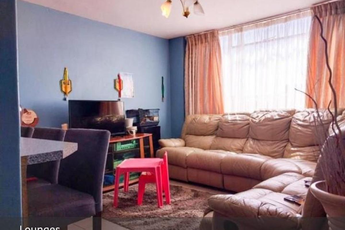 A comfortable living room featuring large windows with curtains, providing natural light and a functional layout for relaxation.