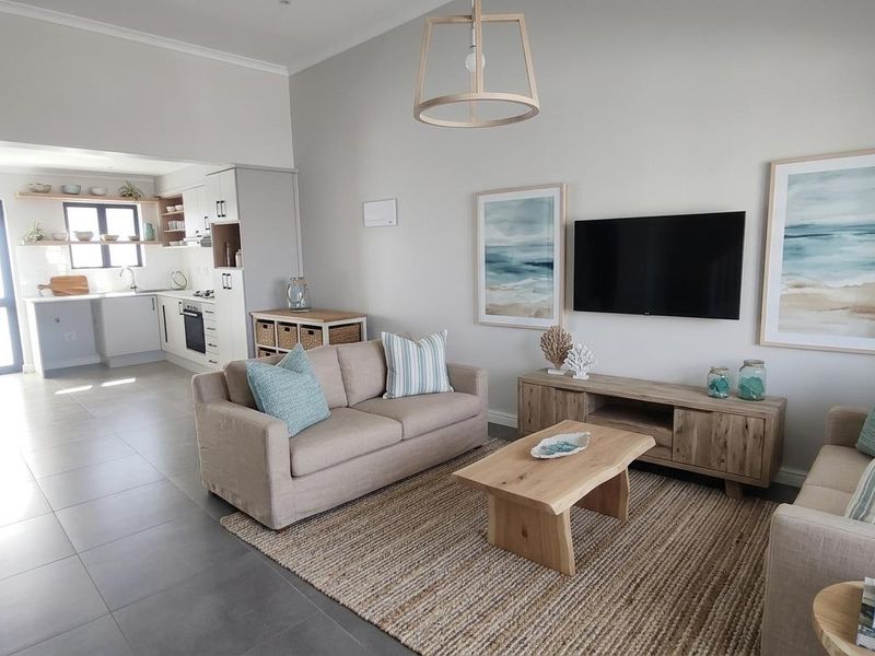 Open-plan living area featuring tiled flooring, a modern kitchen with built-in cabinetry, and a seamless flow between the lounge and cooking space.