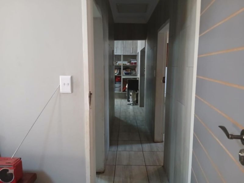 A narrow hallway featuring tiled flooring and built-in cabinetry, providing access to adjacent rooms within the property.