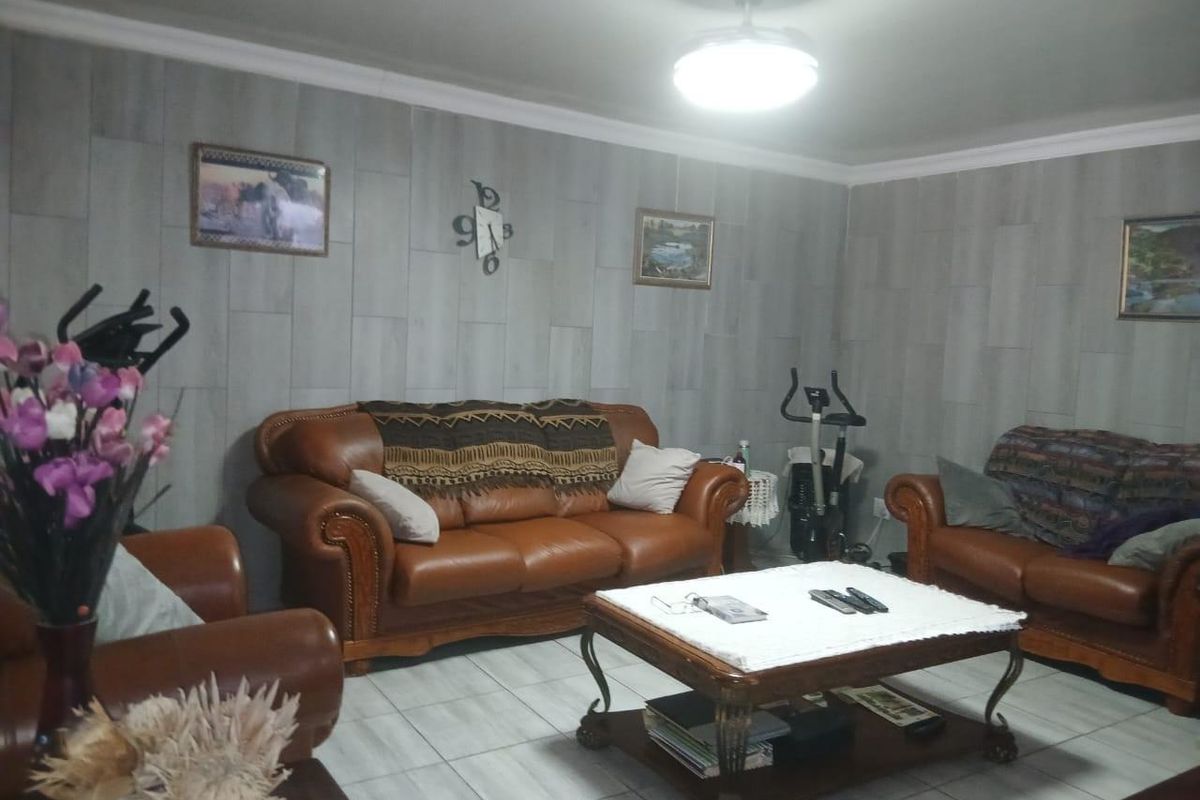 A comfortable living room featuring tiled flooring, coved cornicing, and a central ceiling fan, providing a functional space for relaxation.