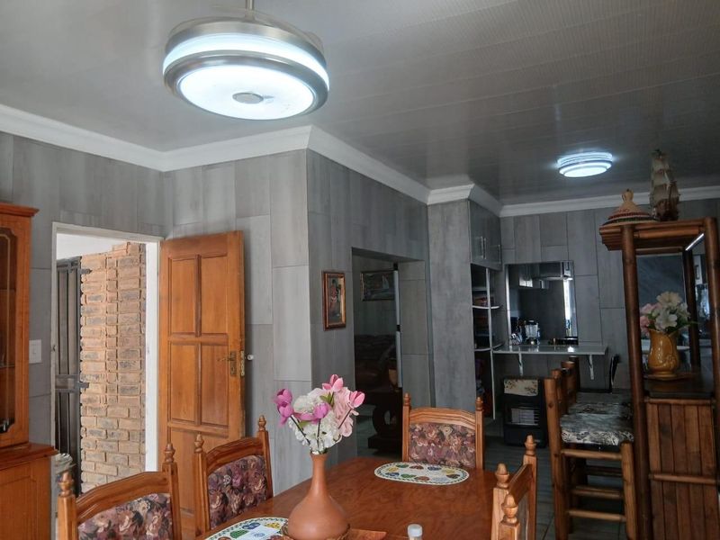 Open plan living and dining area featuring tiled wall finishes, coved cornices, and a breakfast bar connecting to the kitchen space.