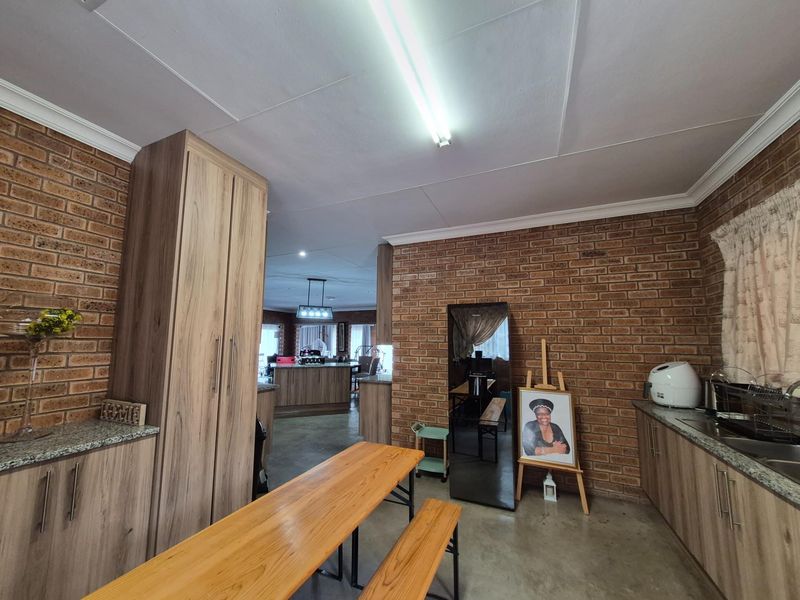 Open-plan kitchen area featuring exposed brick walls, wood-look cabinetry, granite countertops, and a seamless flow into the adjacent living space.