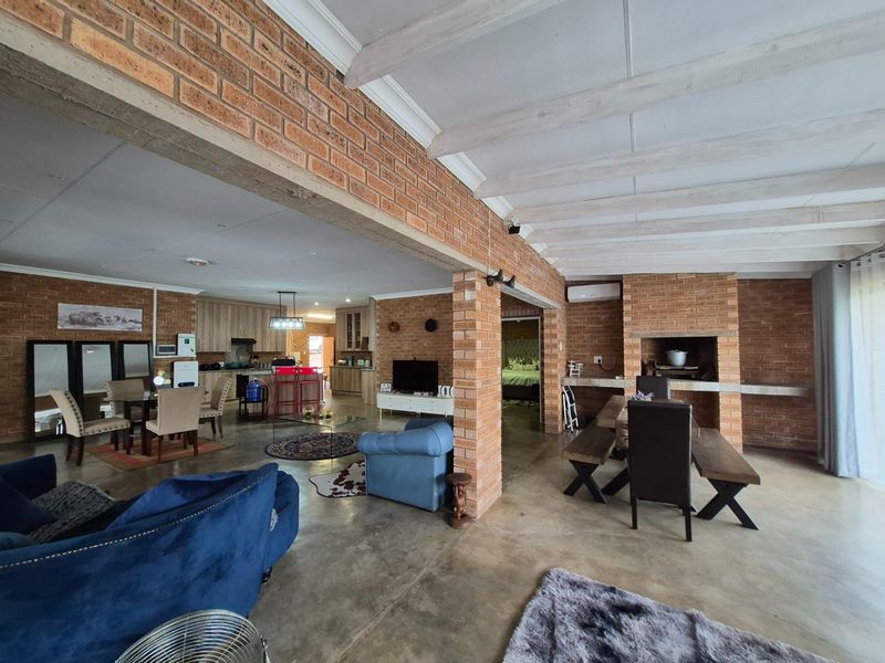 Spacious open-plan living area featuring exposed brick walls, a built-in fireplace, and polished concrete floors, seamlessly connecting to the kitchen and dining space.
