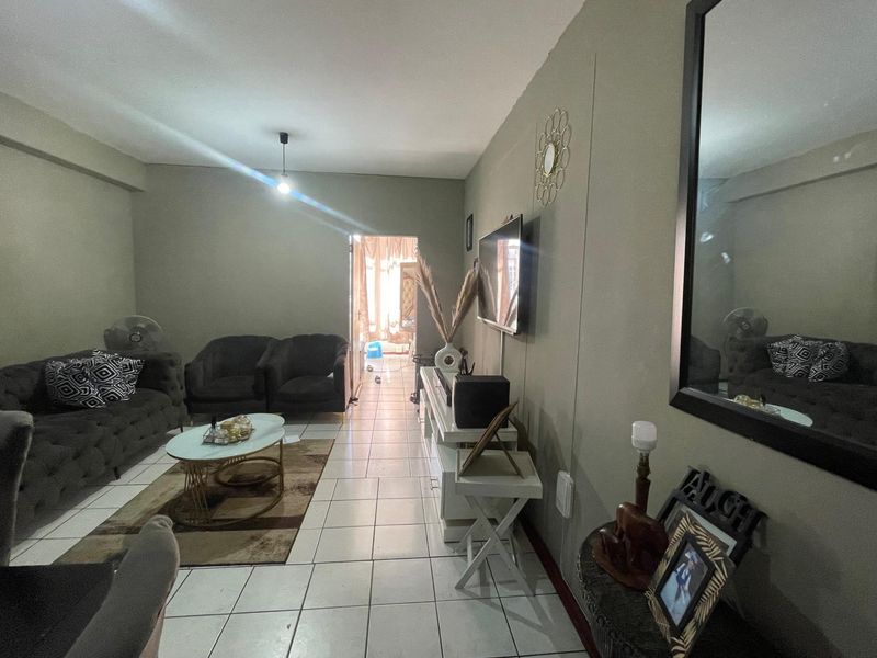 A living room featuring tiled flooring and a wall-mounted television, providing a functional and open living space.