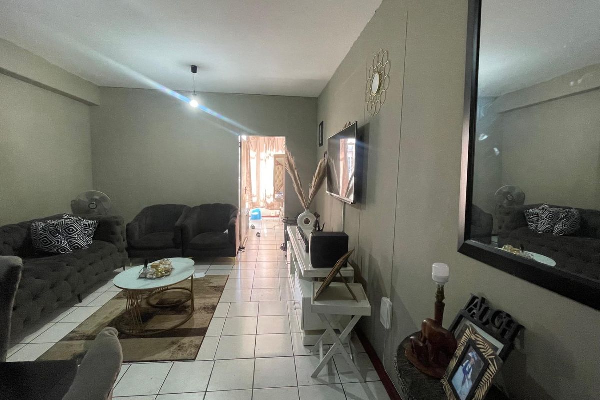 A living room featuring tiled flooring and a wall-mounted television, providing a functional and open living space.
