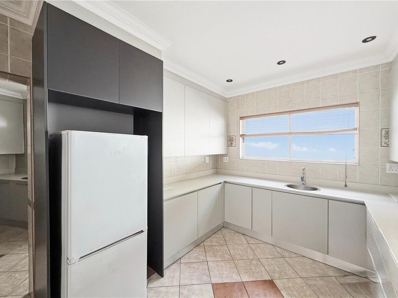 A functional kitchen featuring neutral cabinetry, stone-look countertops, a stainless steel sink, and recessed ceiling lighting.