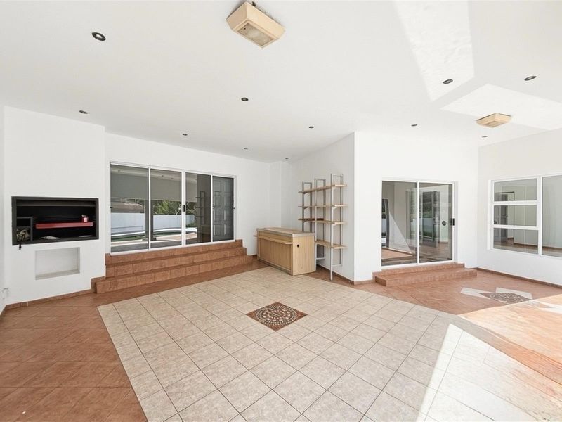 Spacious covered patio area featuring built-in fireplace, tiled flooring, and sliding glass doors providing seamless access to the outdoor pool area.