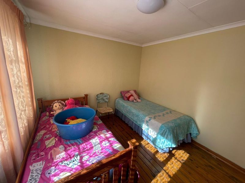 A bedroom featuring timber flooring, coved ceilings, and a window with curtaining.