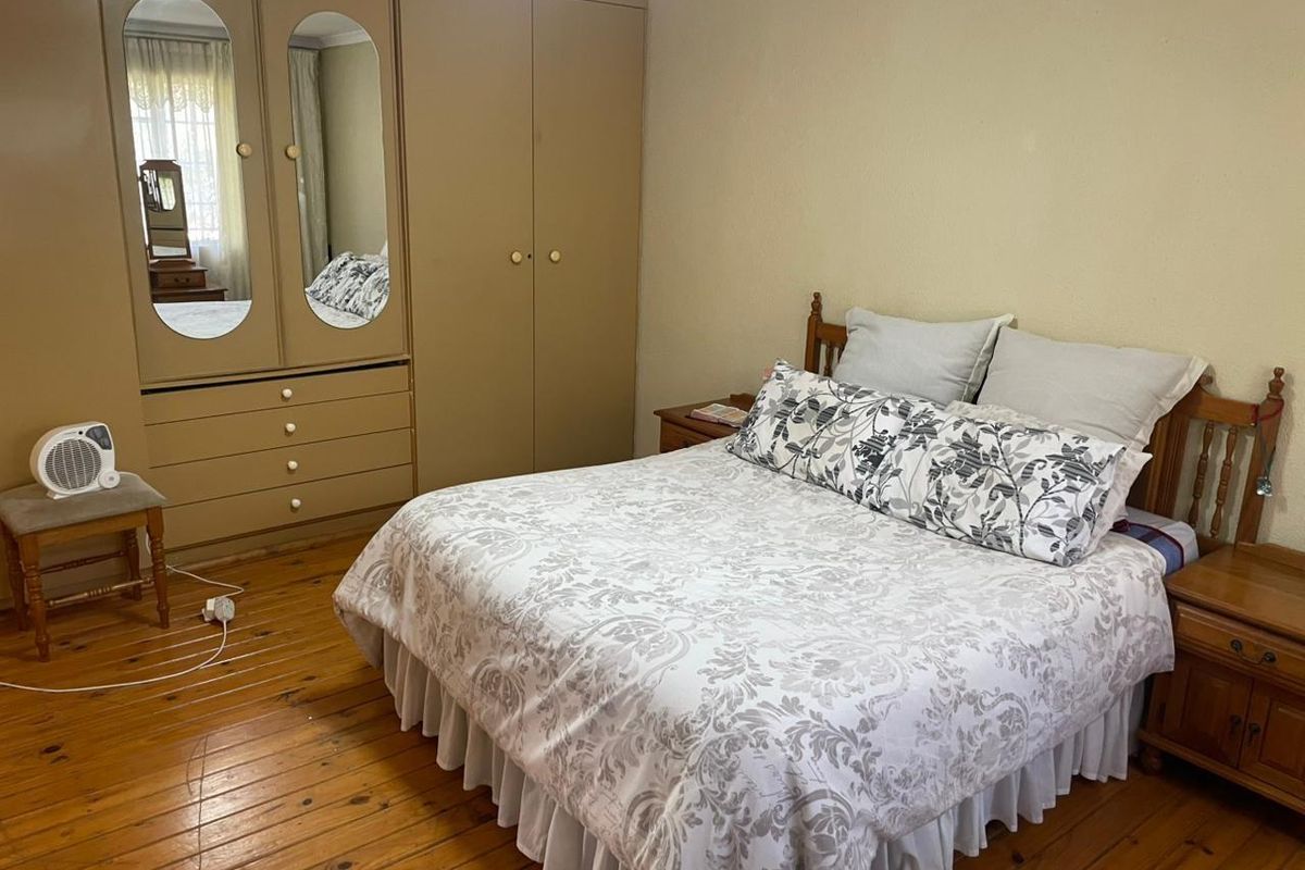 A bedroom featuring original timber flooring and built-in cupboards with integrated mirrors.