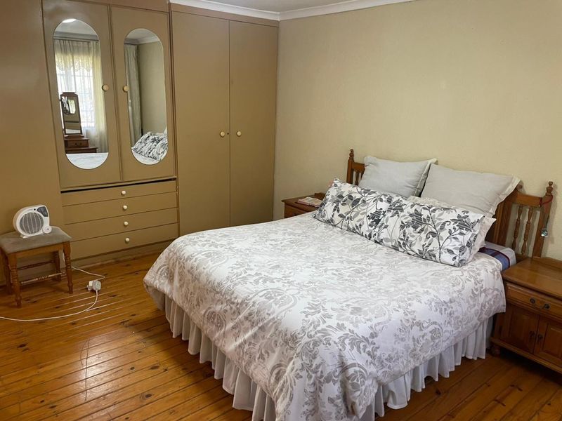 A bedroom featuring original timber flooring and built-in cupboards with integrated mirrors.