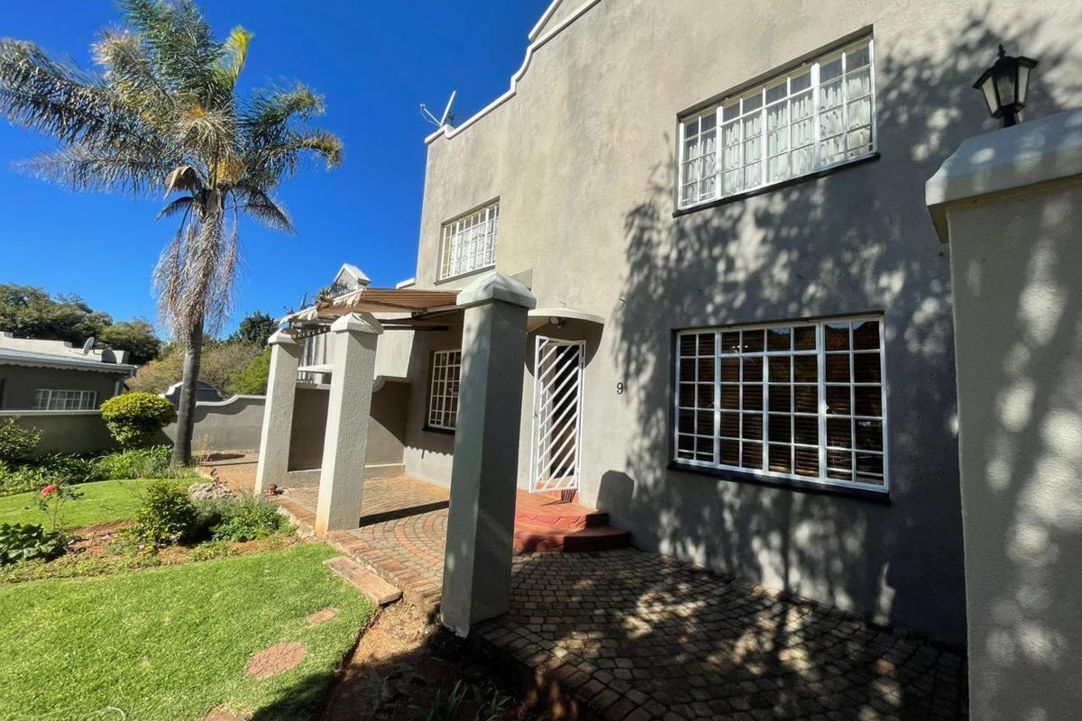 Exterior view of a townhouse featuring a paved patio area, garden space, and traditional window frames.