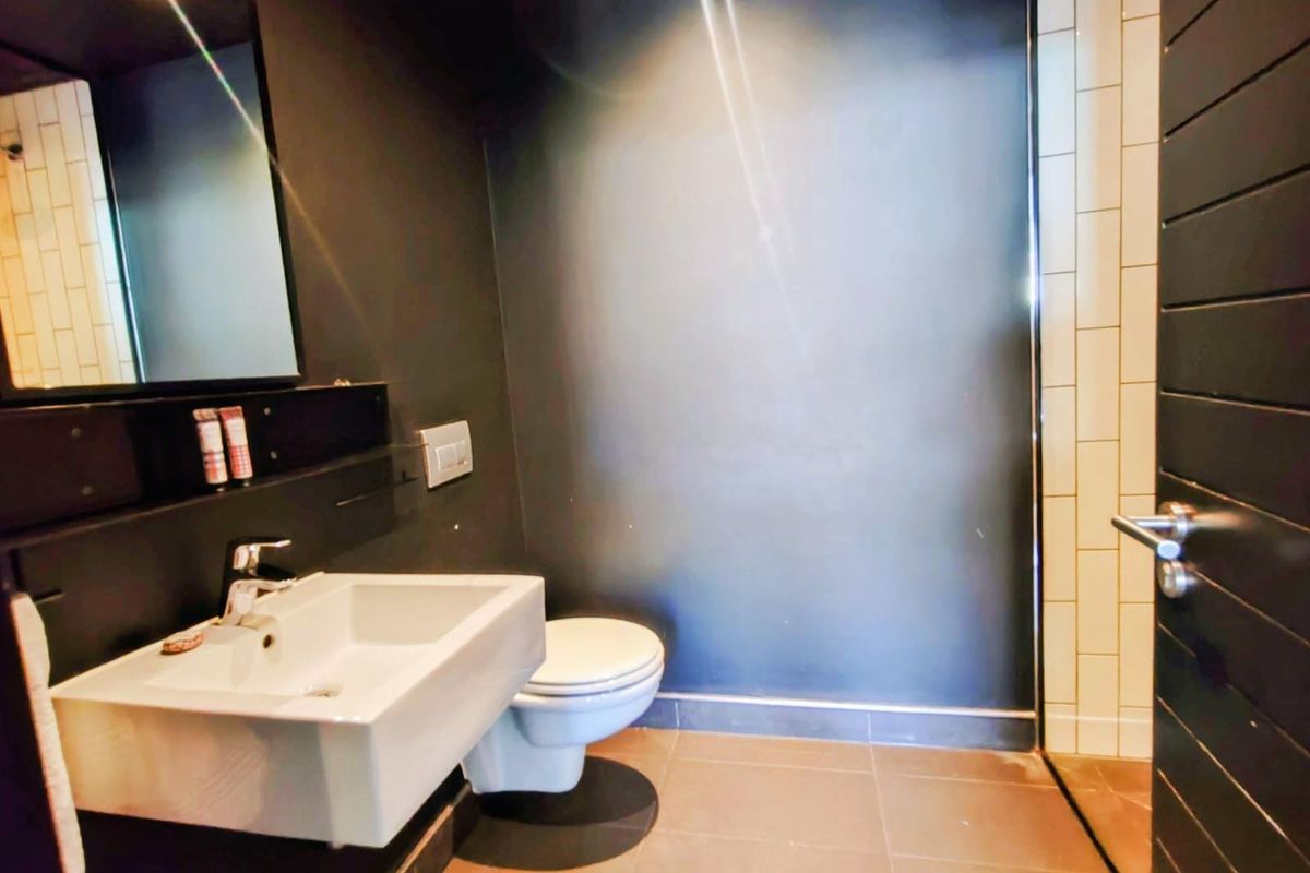 Modern bathroom featuring a wall-mounted basin, sleek dark wall finishes, and tiled flooring with contemporary fixtures.