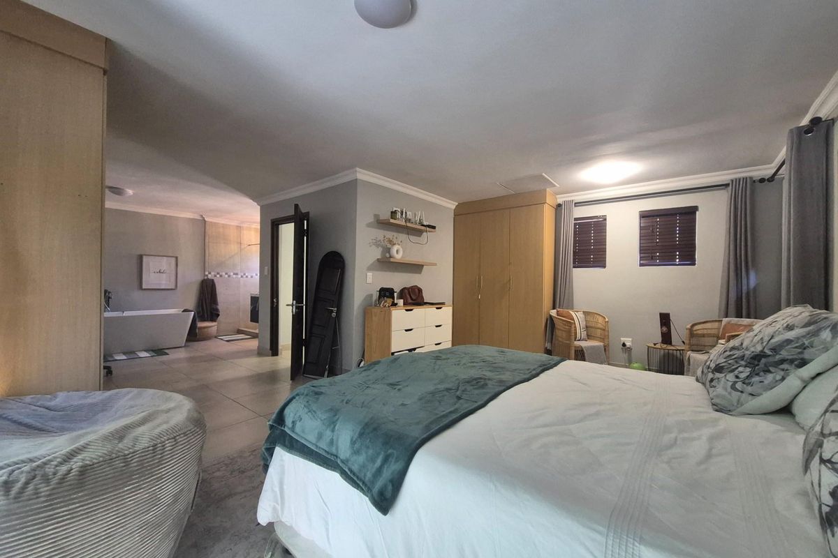 Spacious bedroom featuring built-in wooden cabinetry and an open-plan layout leading to an en-suite bathroom with a freestanding bathtub.