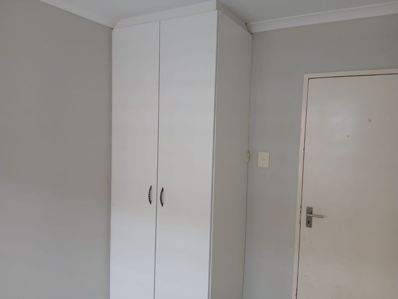 A clean, neutral bedroom featuring a white built-in wardrobe and simple interior finishes, offering a blank canvas for personalization.