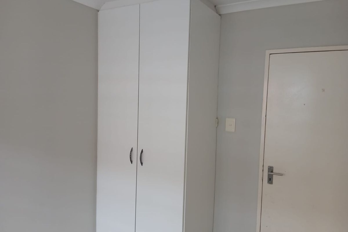 A clean, neutral bedroom featuring a white built-in wardrobe and simple interior finishes, offering a blank canvas for personalization.