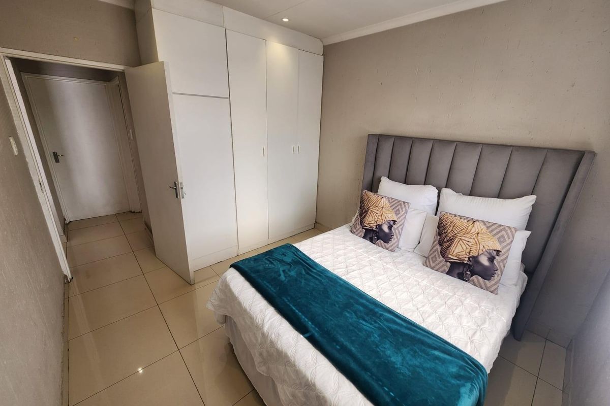 A well-maintained bedroom featuring neutral wall tones, tiled flooring, and built-in white cabinetry providing ample storage space.