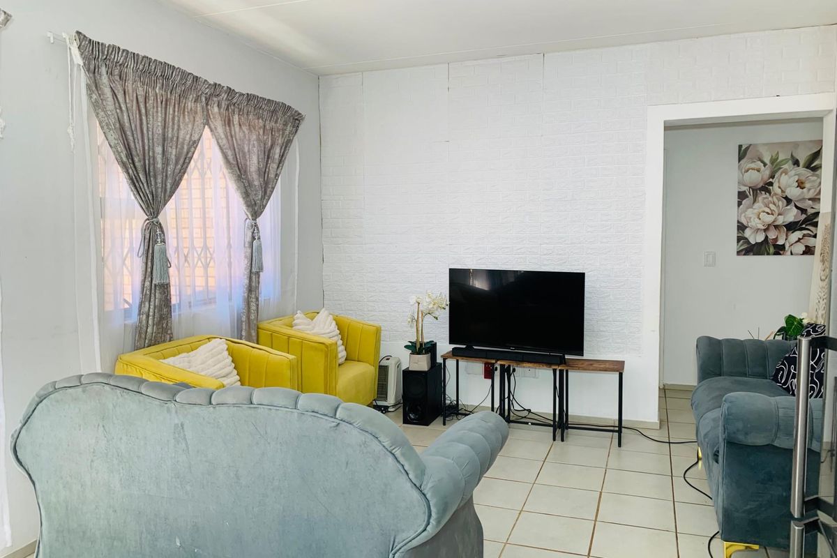 A living room featuring tiled flooring and a textured feature wall, providing a functional space for relaxation and entertainment.
