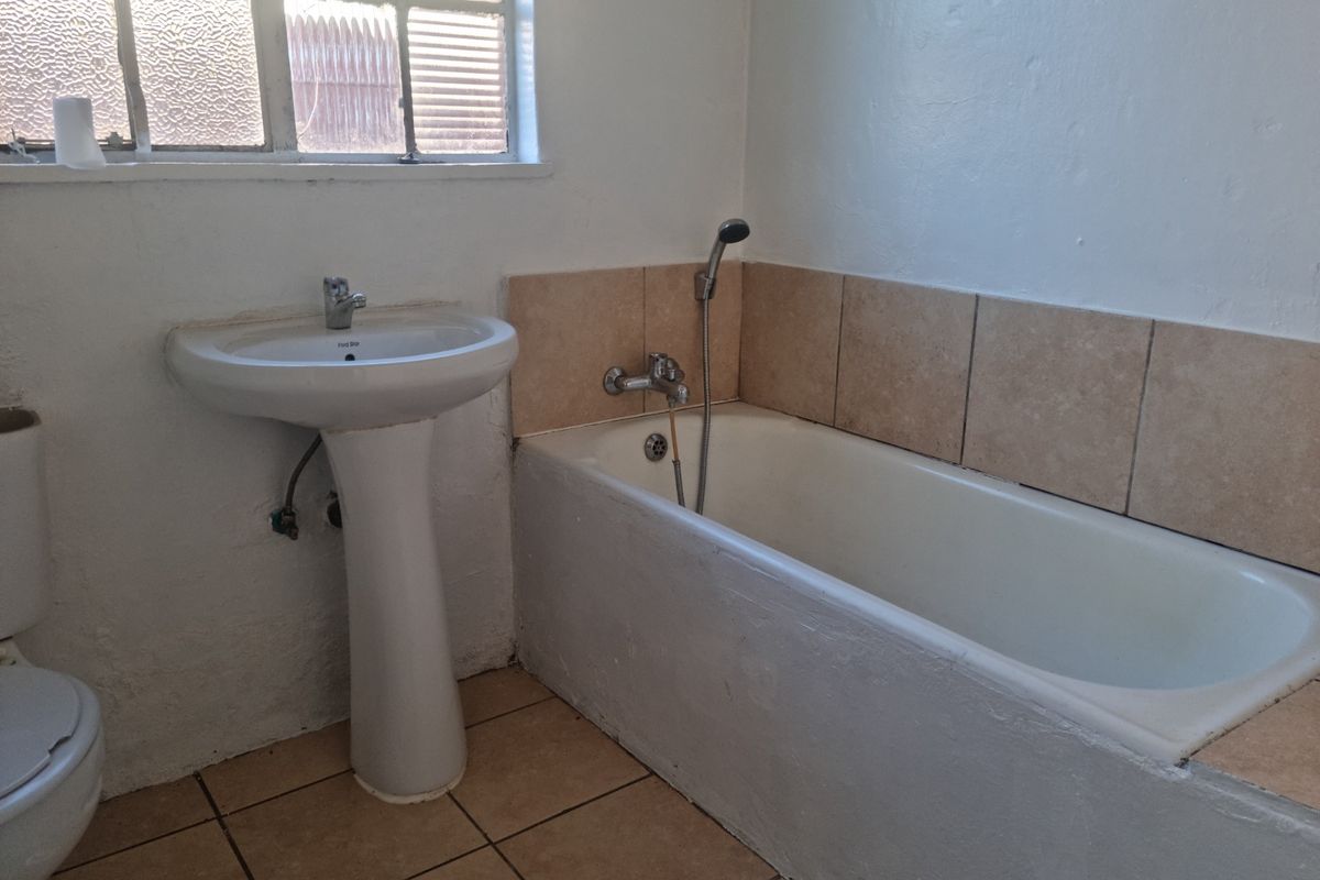 A functional bathroom featuring a pedestal sink, a standard bathtub with a handheld shower attachment, and tiled flooring.