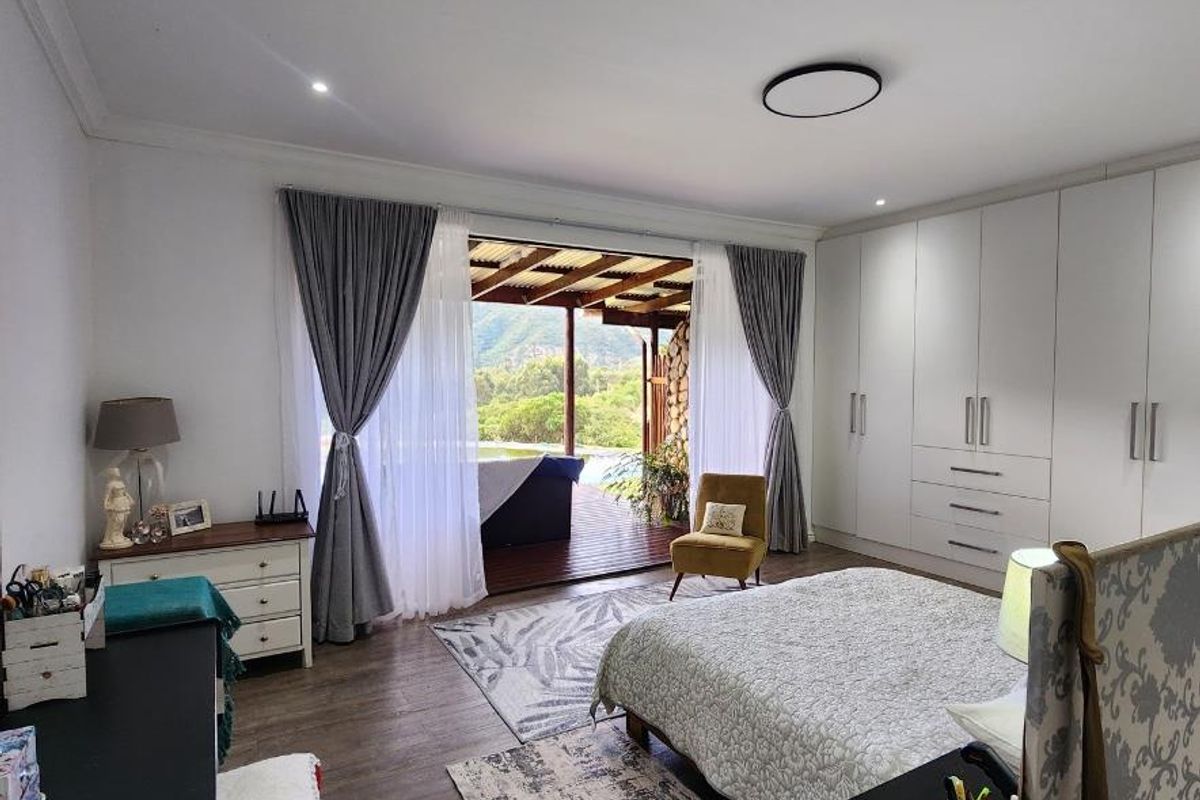 Spacious bedroom featuring extensive built-in cabinetry, modern laminate flooring, and large sliding doors opening onto a covered patio with scenic views.