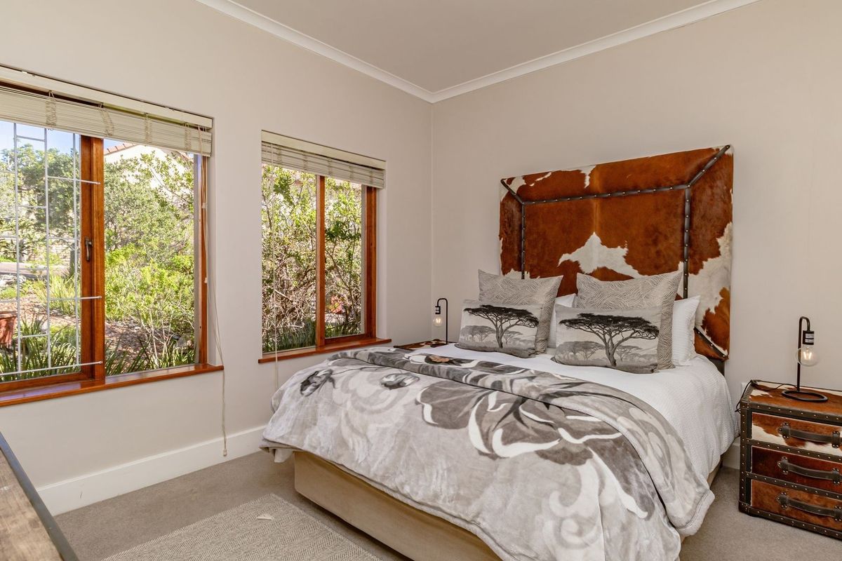 A well-maintained bedroom featuring timber-framed windows with integrated blinds, neutral wall finishes, and carpeted flooring.