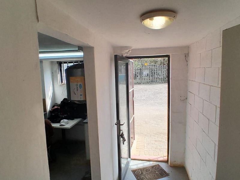 A functional industrial entryway featuring painted block walls, a secure metal door, and direct access to an exterior paved area.