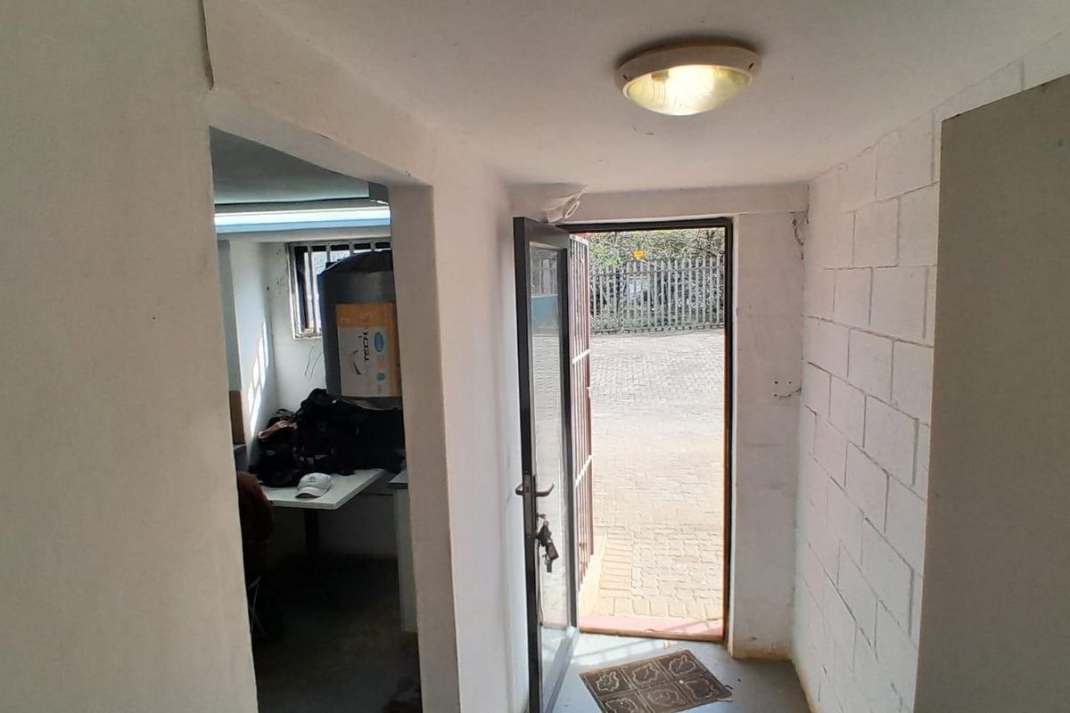 A functional industrial entryway featuring painted block walls, a secure metal door, and direct access to an exterior paved area.