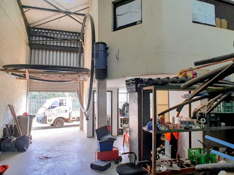 Industrial warehouse space featuring high ceilings, roller shutter door access, and mezzanine level, suitable for storage or workshop operations.