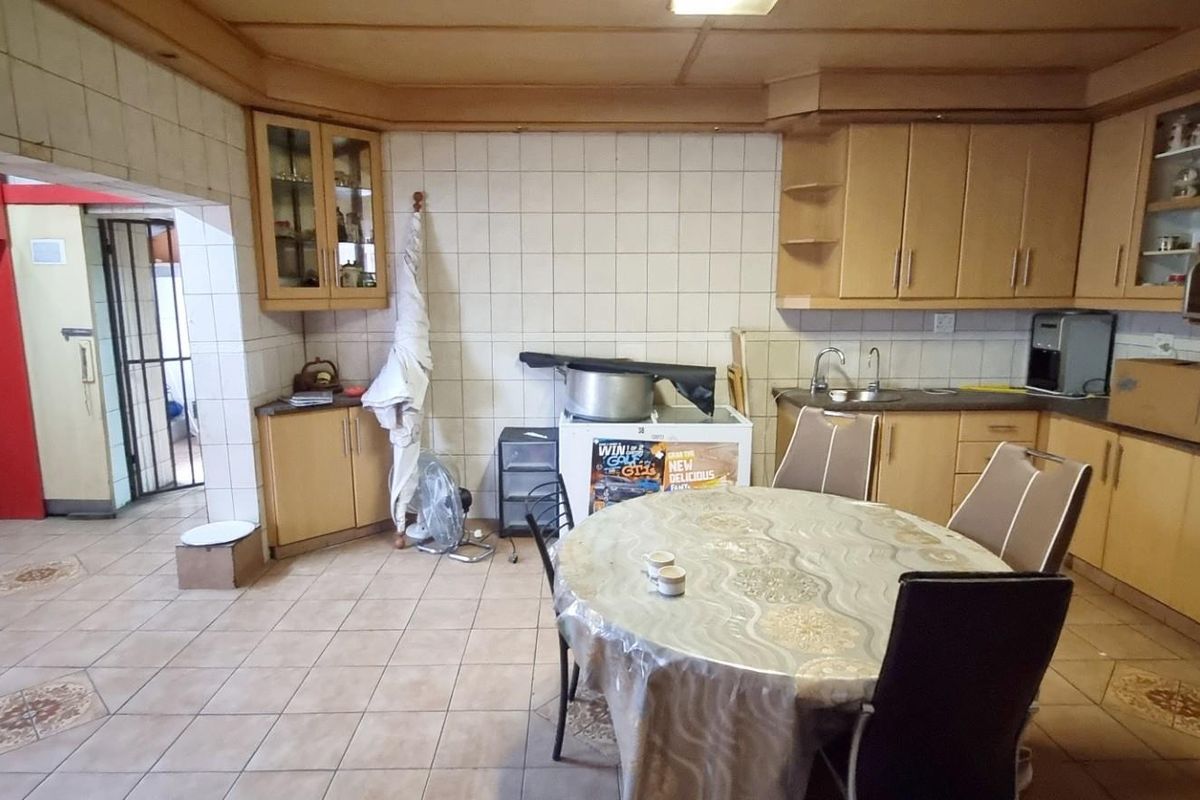 Spacious kitchen featuring wooden cabinetry, tiled flooring, and a functional layout with integrated sink and built-in oven.