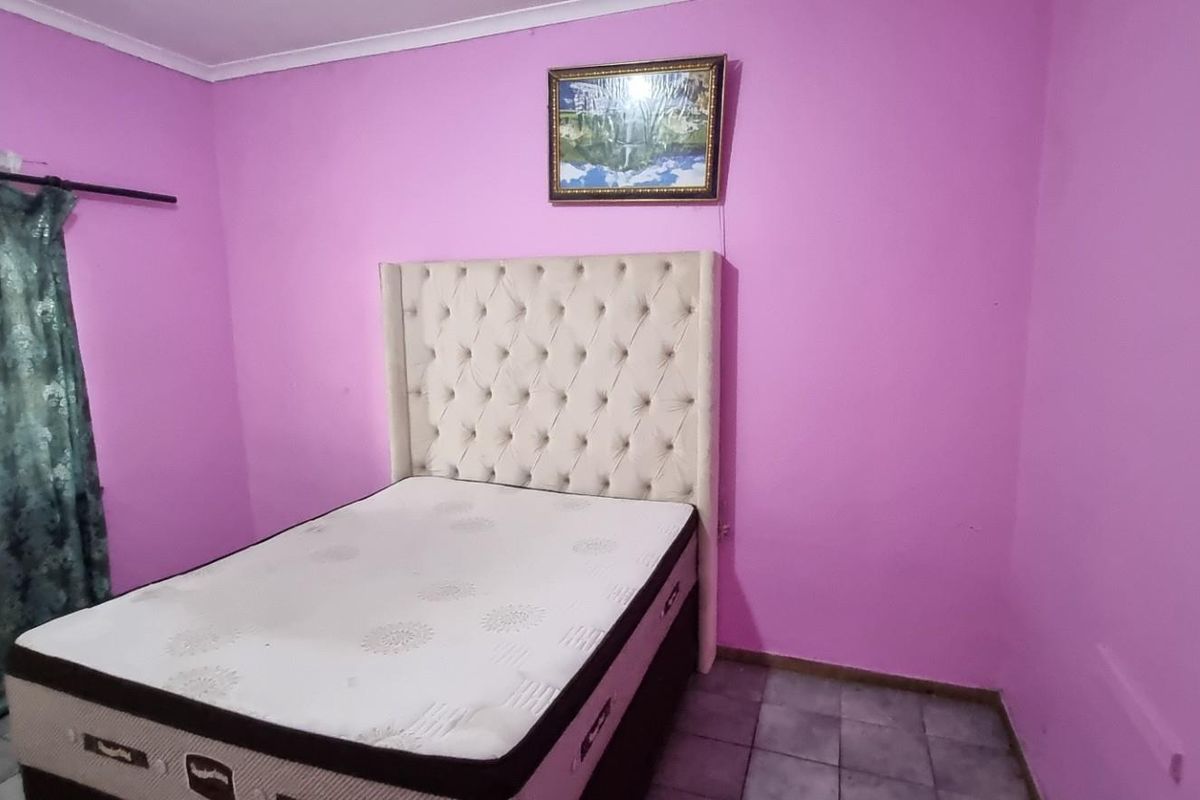 A bedroom featuring tiled flooring and pink painted walls, providing a functional space for rest.