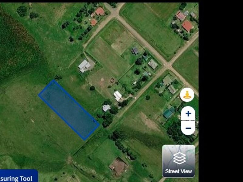 An aerial view showing the vacant residential land plot highlighted in blue within a rural neighborhood setting.
