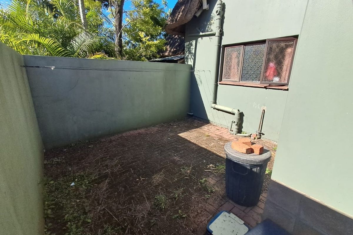 A small, private rear courtyard area featuring paved flooring and a boundary wall, adjacent to the main house structure.