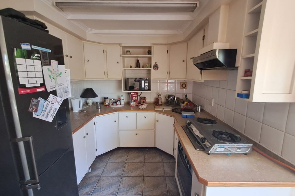 A dated kitchen featuring U-shaped cabinetry, tiled backsplash, built-in oven, and a gas cooktop, offering a functional layout ready for modernization.