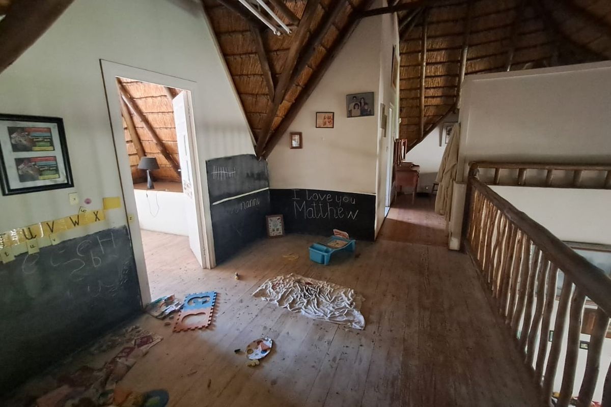 An attic-style living space featuring exposed thatch roofing, timber flooring, and a wooden balustrade overlooking the lower level.