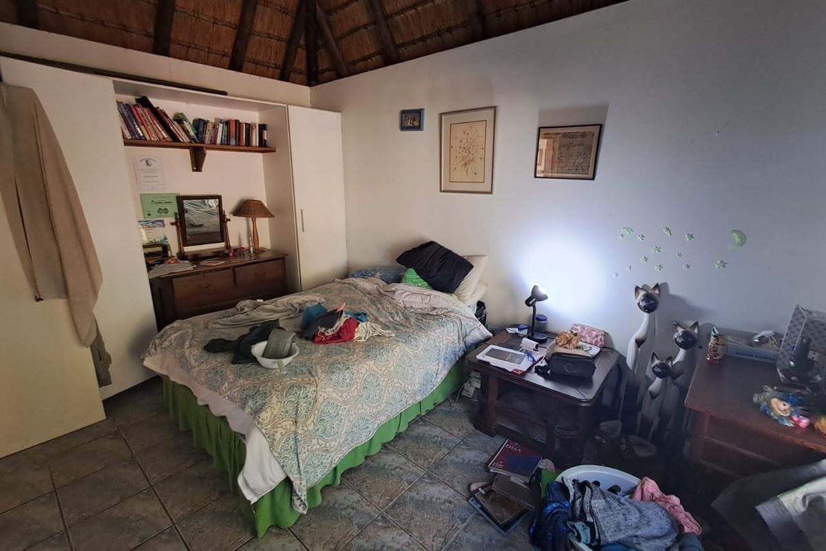 A bedroom featuring a high thatched roof, tiled flooring, and built-in cabinetry.