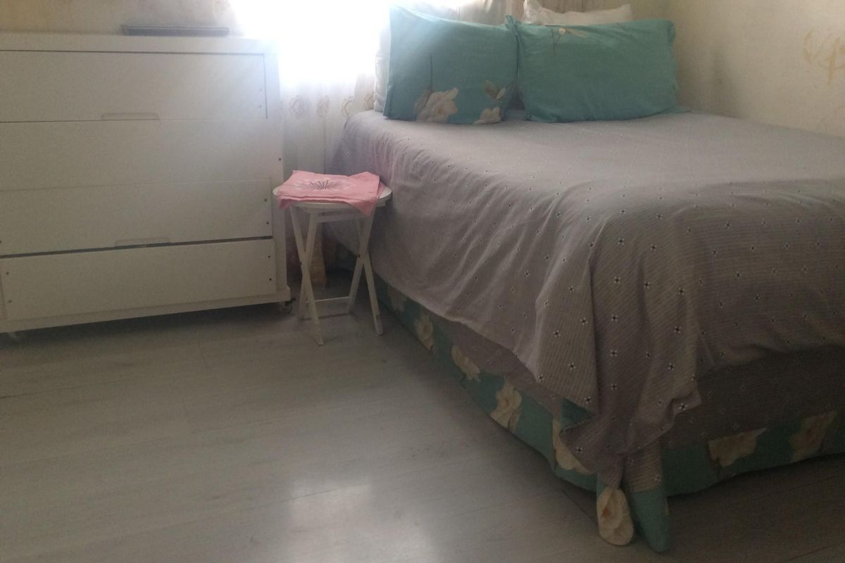 A bedroom featuring light-toned laminate flooring and neutral wall finishes, providing a functional space for rest.