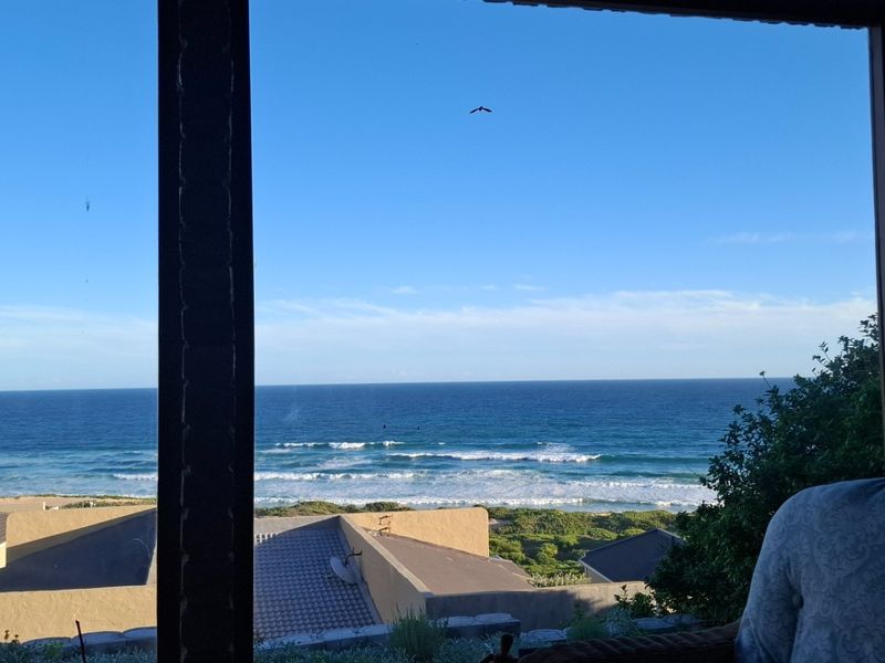 A scenic view of the ocean and coastline captured from an elevated position, showcasing the property's prime coastal location.