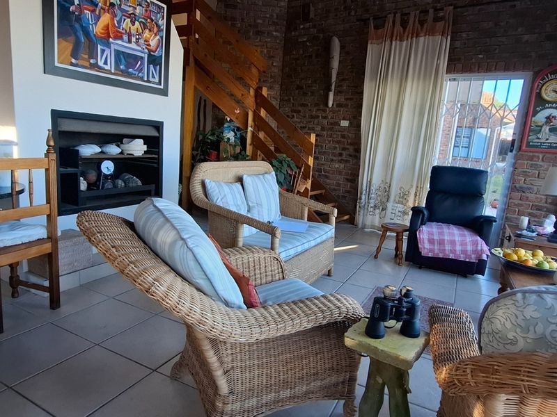 Open plan living area featuring exposed brick walls, tiled flooring, a built-in fireplace, and a wooden staircase leading to the upper level.