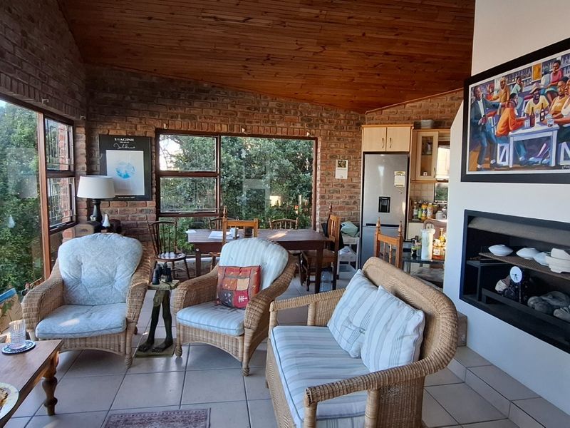Open plan living and dining area featuring exposed brick walls, timber-clad vaulted ceilings, large windows, and a built-in fireplace.