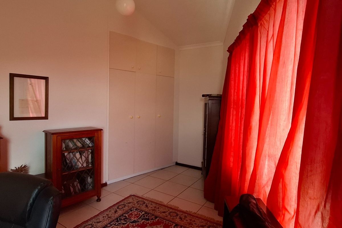 A bedroom featuring built-in cupboards and tiled flooring, offering a functional space with natural light.