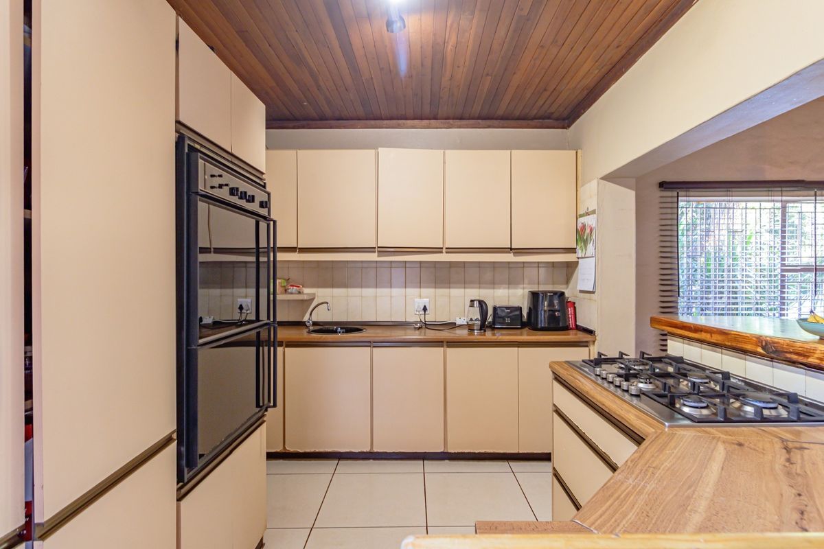 A functional kitchen featuring built-in cabinetry, a double wall oven, a gas cooktop, and a timber-paneled ceiling.