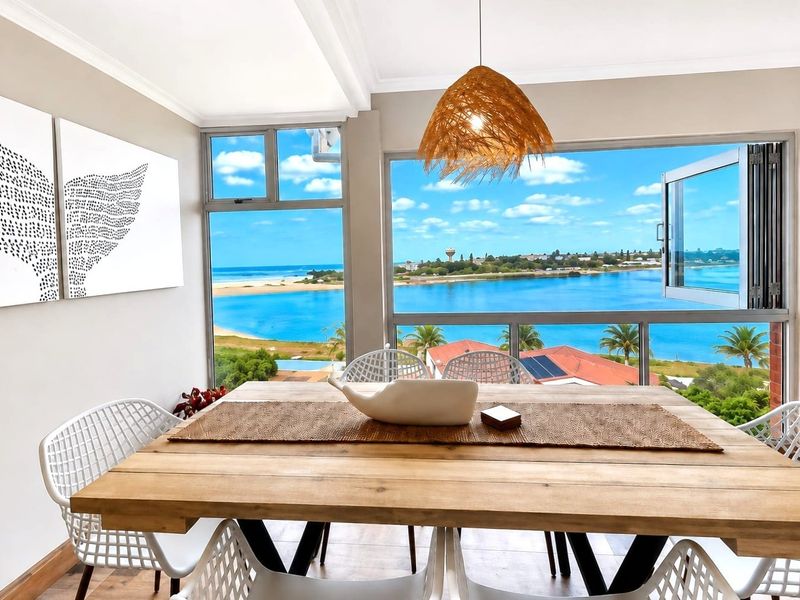 Bright dining area featuring large windows with expansive coastal and lagoon views, complemented by modern finishes and natural light.