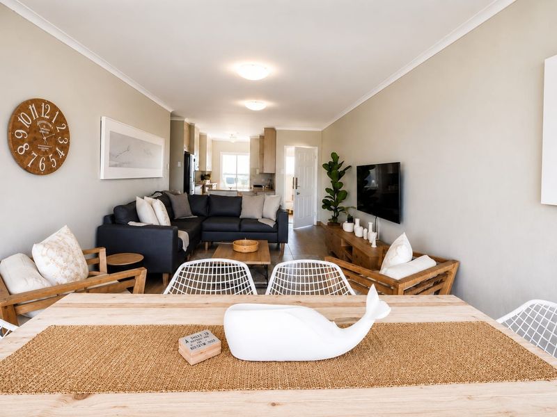 An open-plan living and dining area featuring neutral walls, tiled flooring, and a seamless transition into the kitchen space.