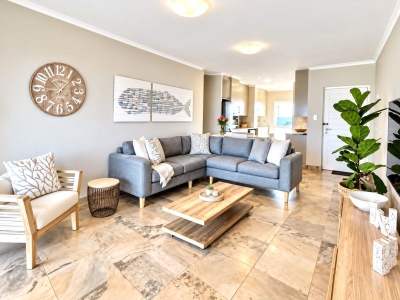 Spacious open-plan living area featuring neutral tiled flooring, recessed lighting, and a seamless transition into a modern kitchen space.