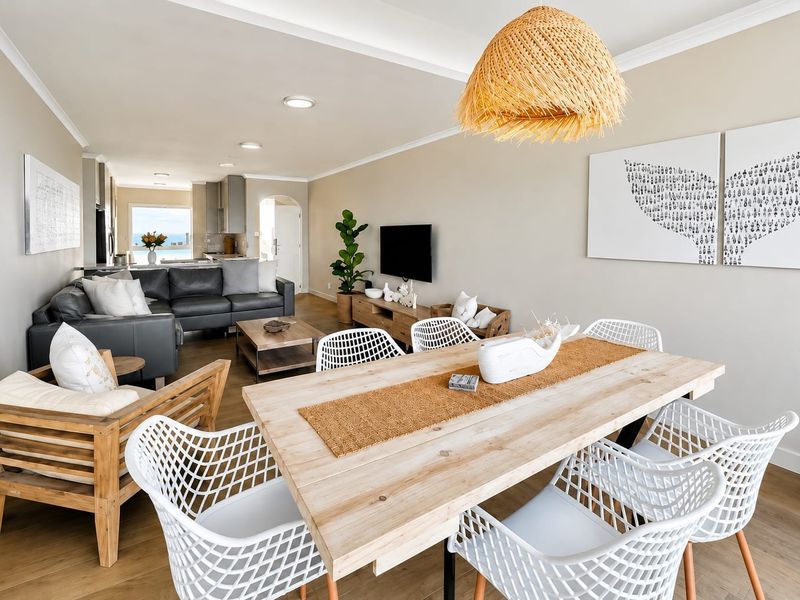 Spacious open-plan living and dining area featuring modern laminate flooring, recessed lighting, and a seamless flow into the kitchen space.