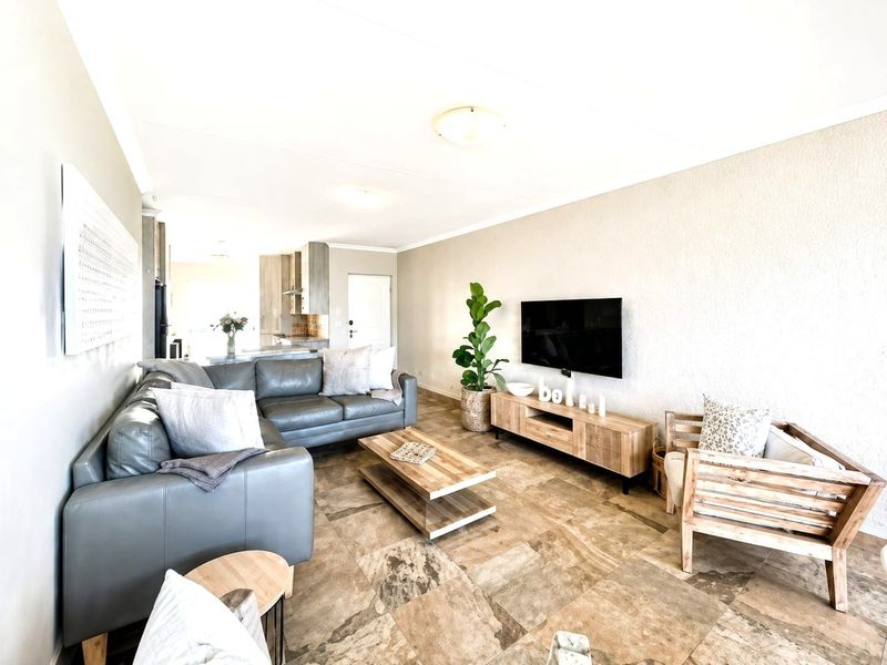 An open-plan living area featuring tiled flooring and a seamless transition into the kitchen space, creating a bright and functional living environment.