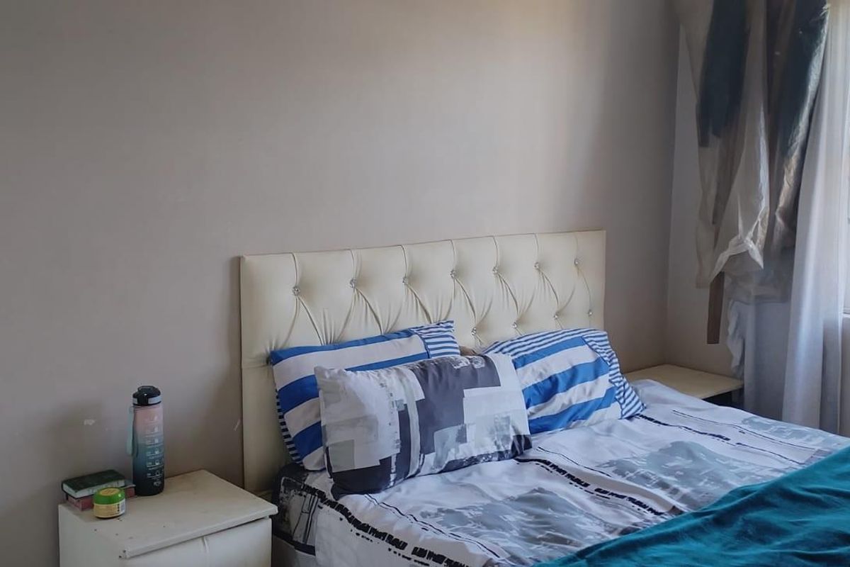 A standard bedroom featuring a window with a fitted security gate.