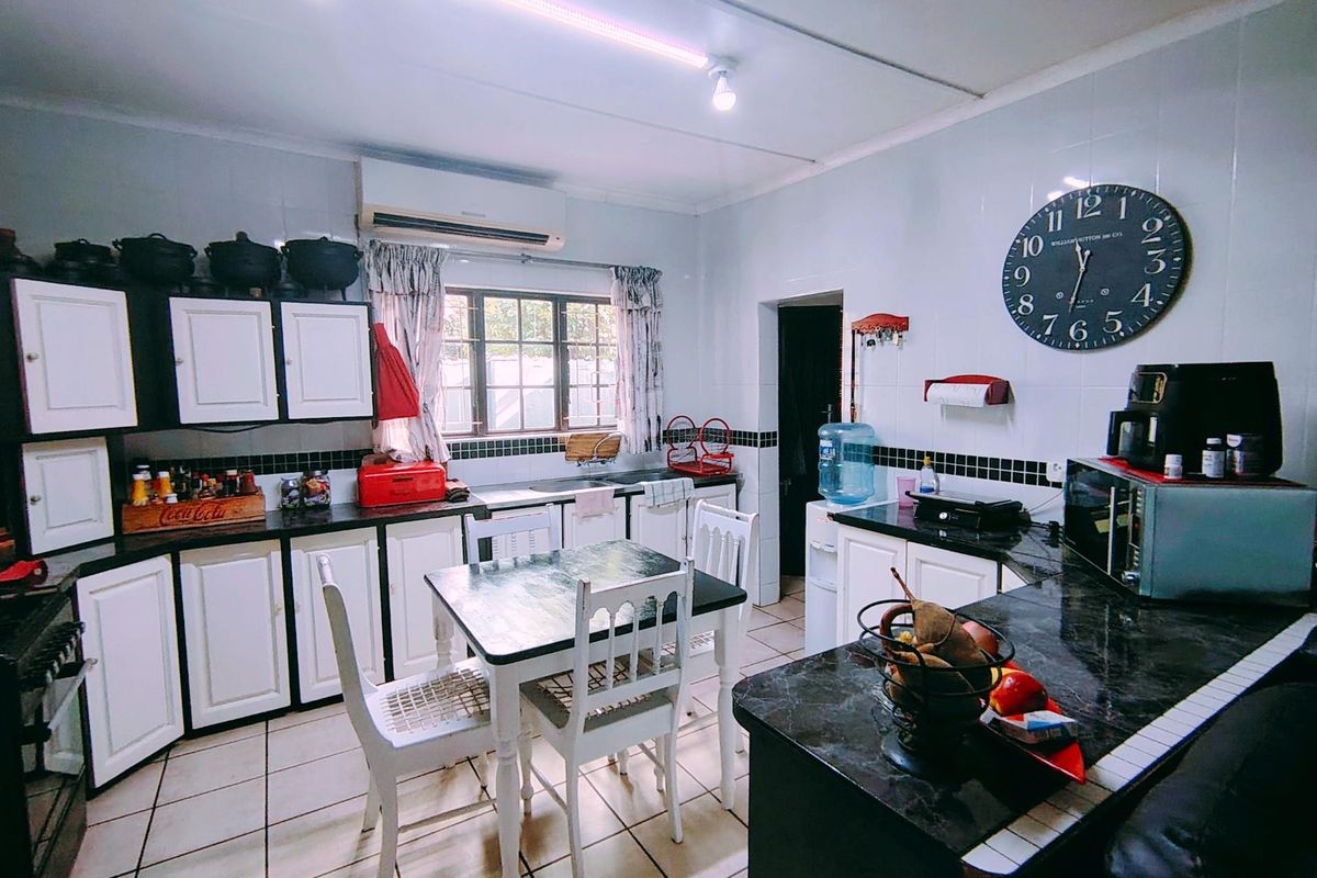 A functional kitchen featuring built-in cabinetry, dark laminate countertops, tiled splashbacks, and tiled flooring, providing a practical workspace with integrated storage.