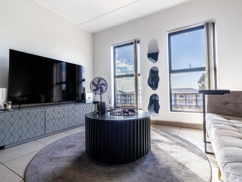 A bright living room featuring large windows, tiled flooring, and a modern built-in media console unit.