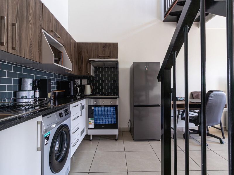 Modern kitchen featuring dark wood cabinetry, black subway tile backsplash, granite countertops, integrated oven, and a built-in washing machine.