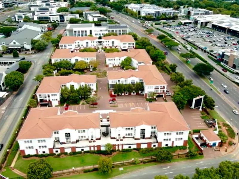 Aerial view of a commercial office park complex featuring multiple multi-story buildings with terracotta tiled roofs and landscaped grounds.